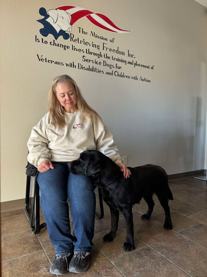 Service Dog performing Deep Pressure Therapy (DPT) by resting its head on a client's lap to provide comfort and anxiety relief.